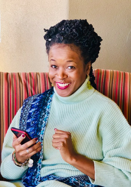 Dana smiling warmly while holding her phone
